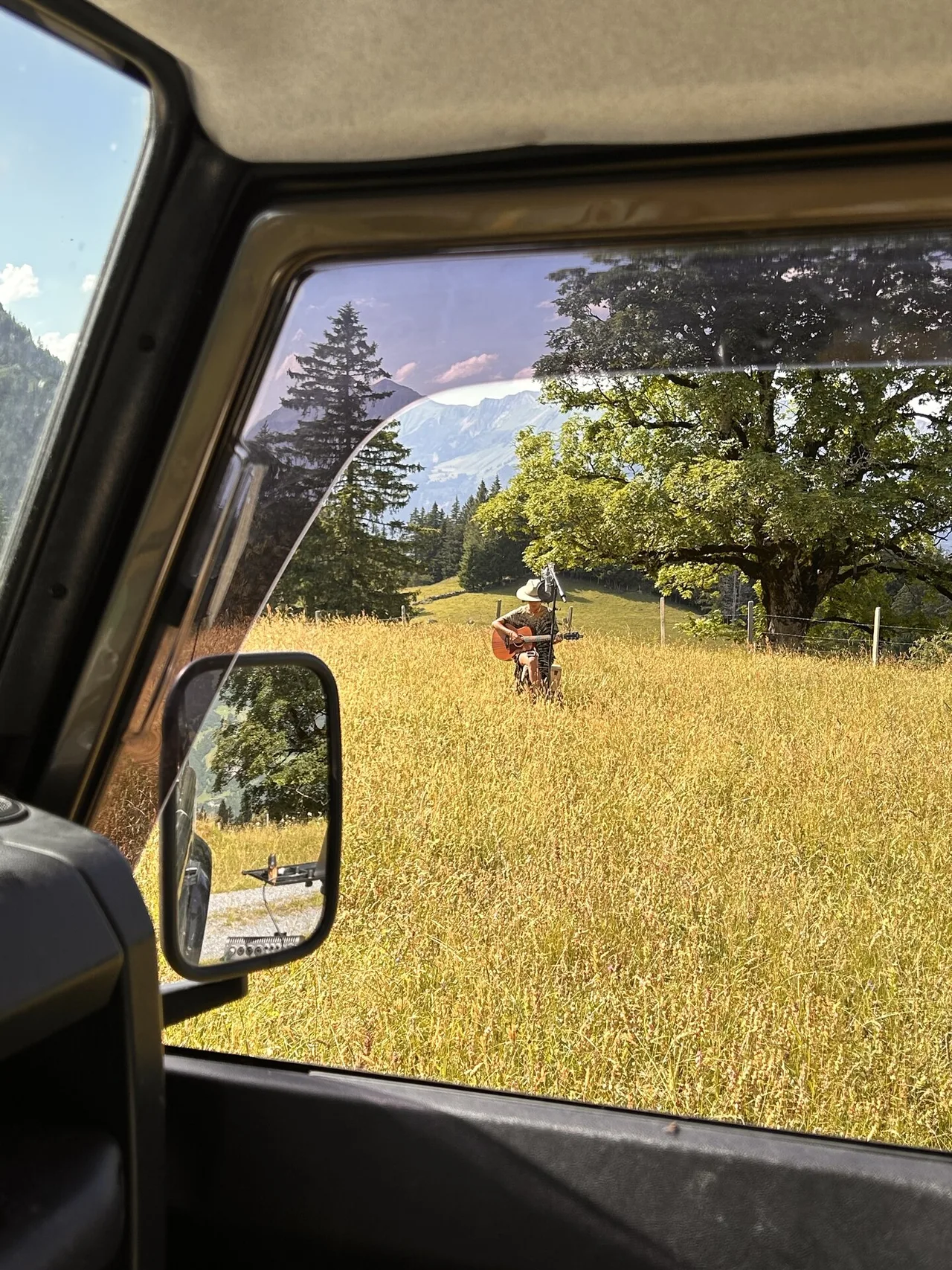 Blick aus dem Defender auf eine Gitarrenaufnahme mit Mikrofon auf einer Wiese in den Schweizer Alpen